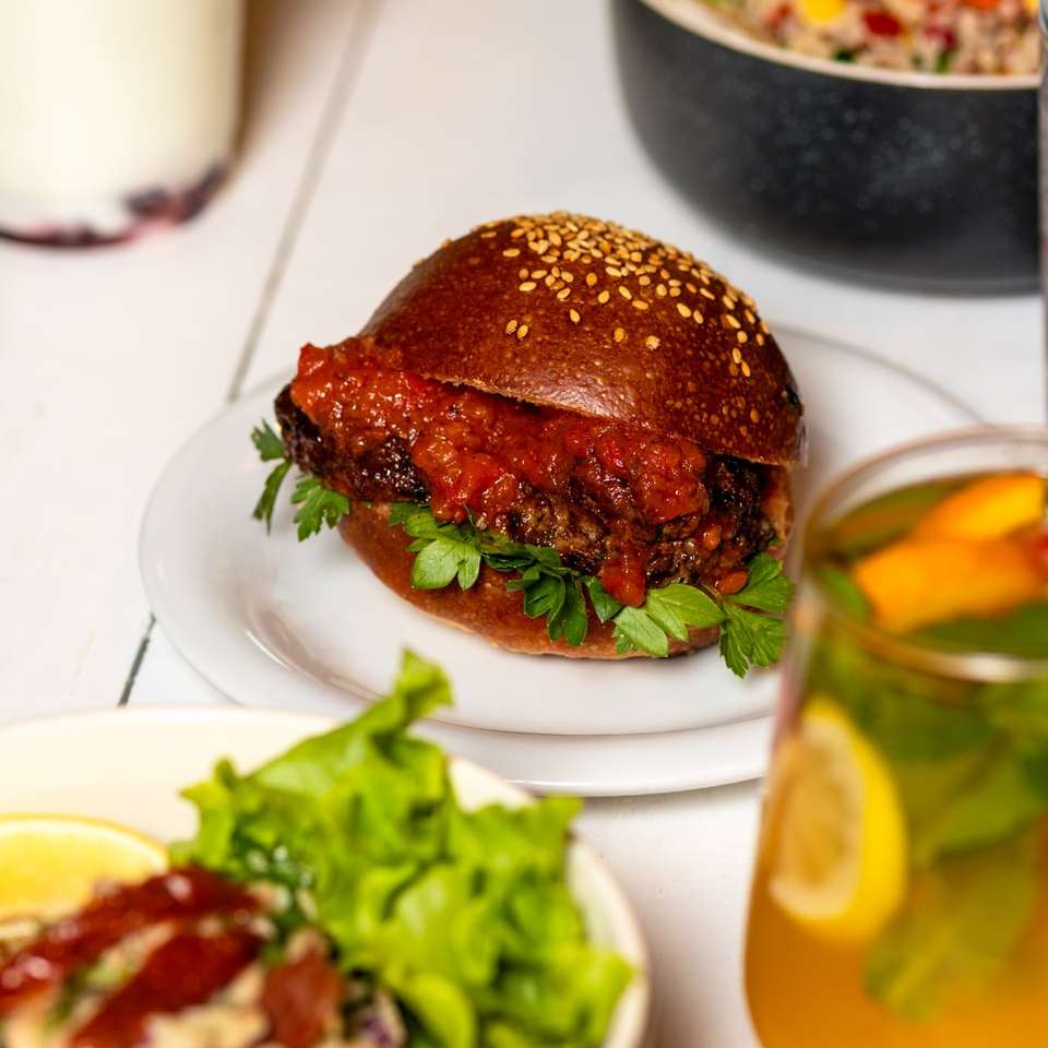 hamburger op witte keramische plaat naast helder drinkglas online puzzel