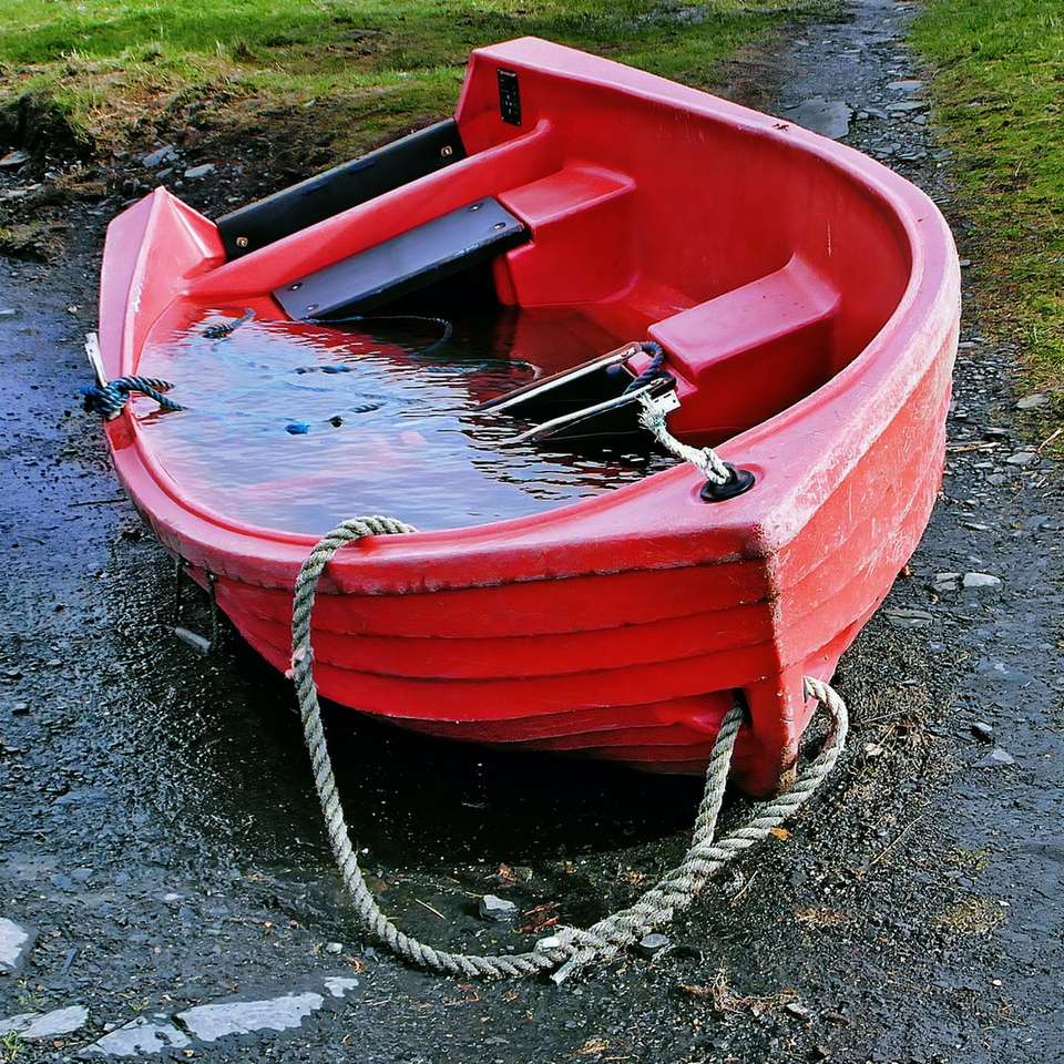 rotes und weißes Boot auf grauem Sand während des Tages Schiebepuzzle online