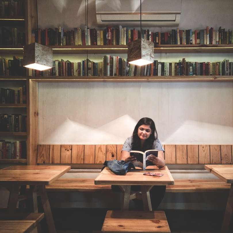 kvinna läser bok inne i biblioteket Pussel online