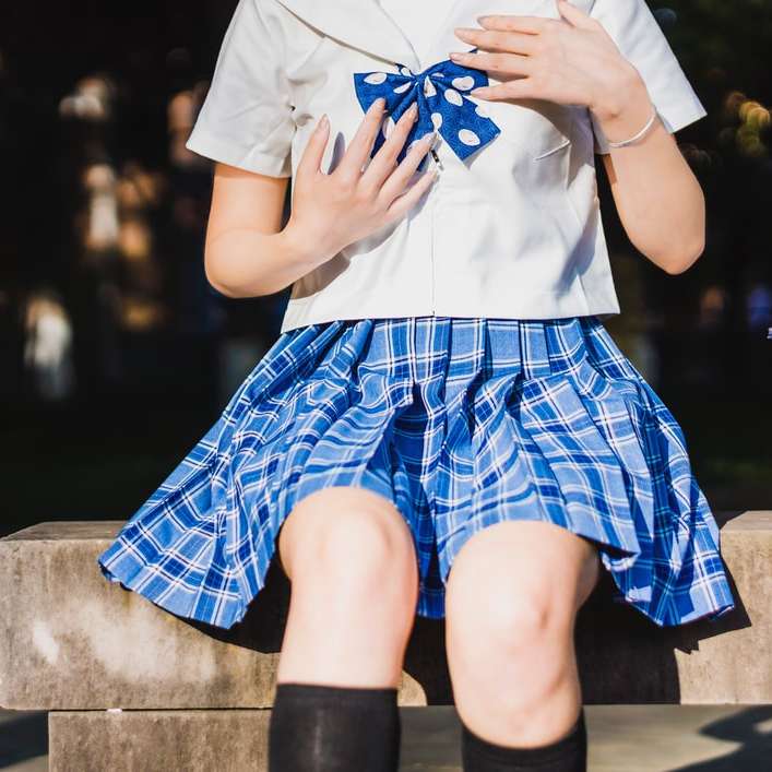személy fehér és kék iskolai egyenruhát ül a strandon csúszó puzzle online