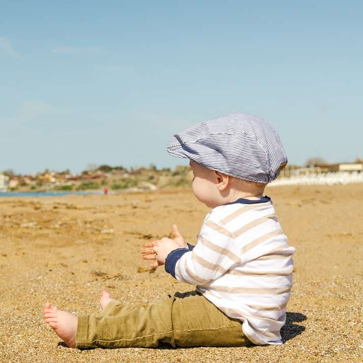 Сидящий малыш на берегу моря в дневное время раздвижная головоломка онлайн
