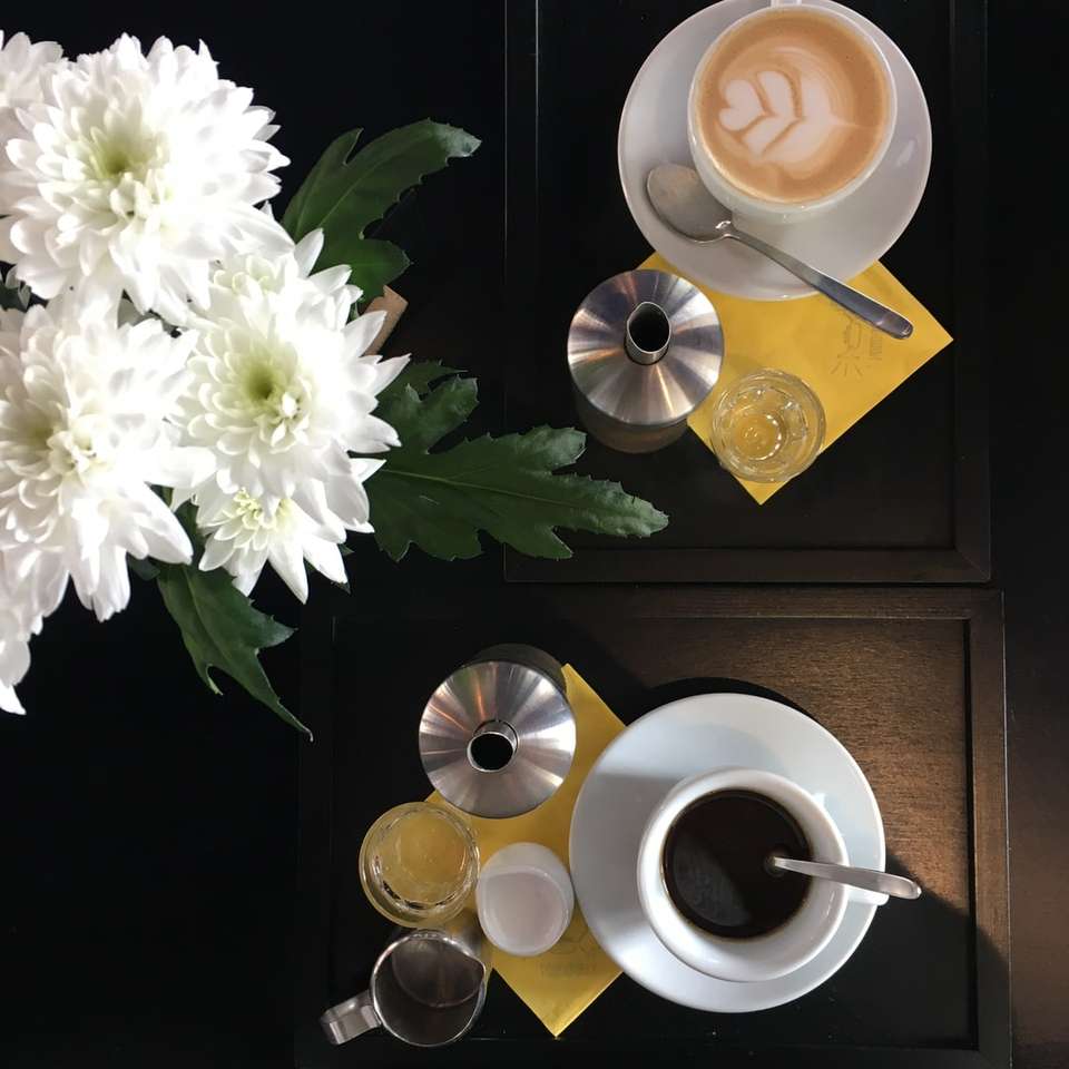 чашка кави біля білих квітів розсувний пазл онлайн
