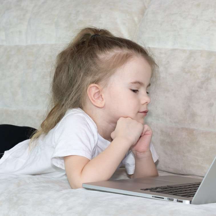 garota em uma camiseta branca usando um laptop prata puzzle online
