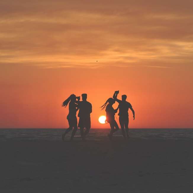 silhouetfoto van vier mensen die op zand dansen schuifpuzzel online