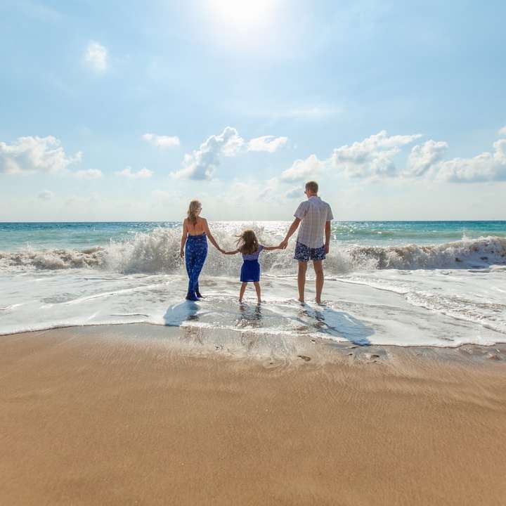 мъж, жена и дете, хванати за ръце на морския бряг онлайн пъзел