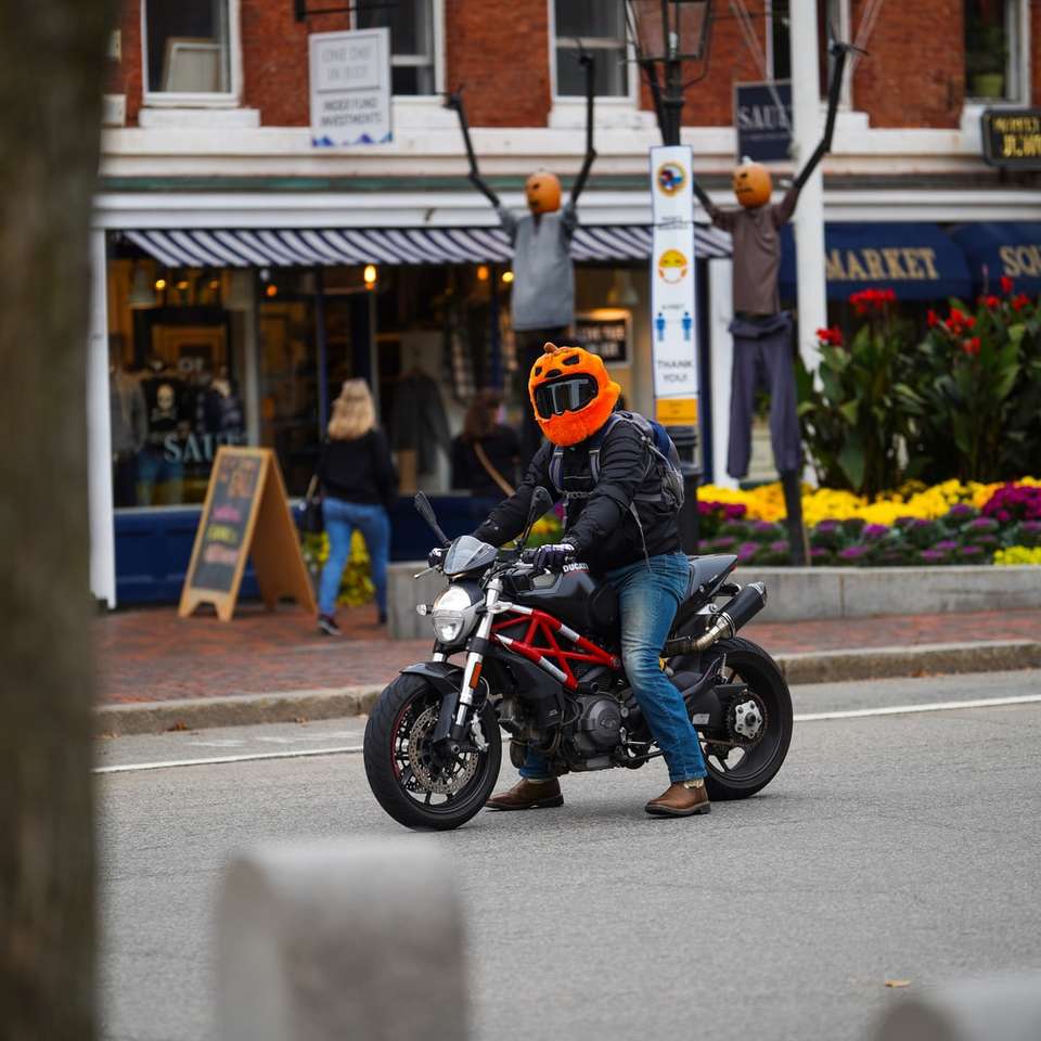 道路で黒いオートバイに乗ってオレンジ色のヘルメットの男 オンラインパズル