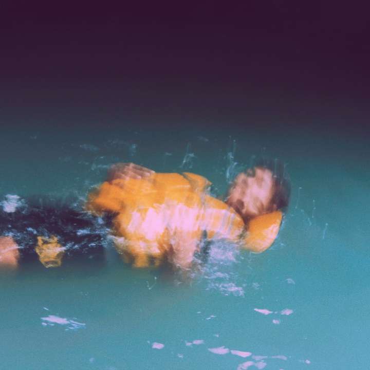 човек във вода с оранжеви и жълти светлини плъзгащ се пъзел онлайн