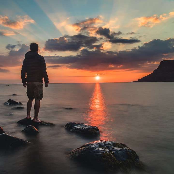 man staande op steen kijken naar zonsondergang online puzzel