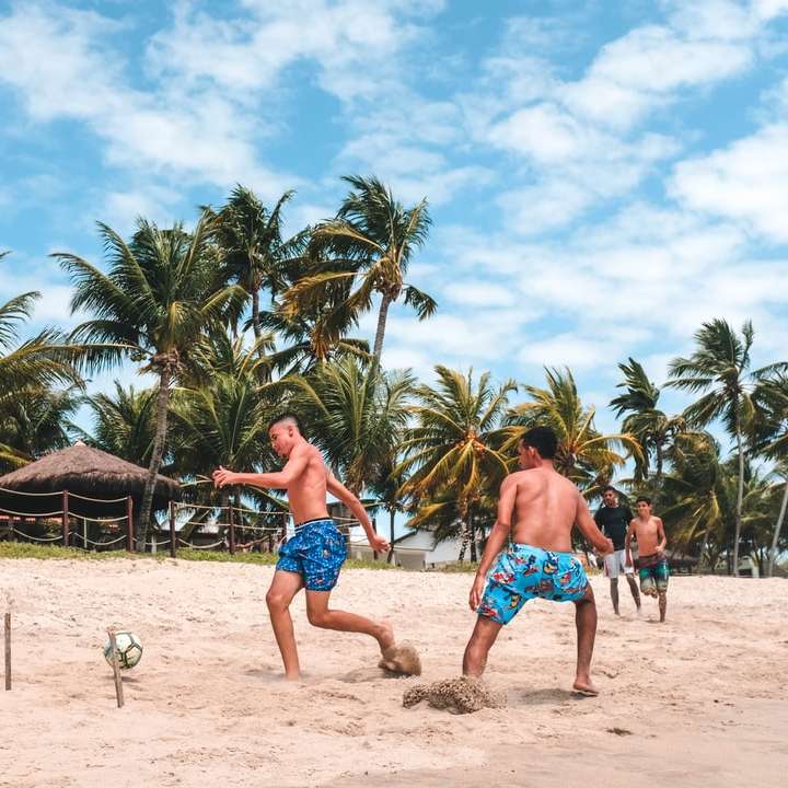 mehrere Männer spielen Fußball auf Strandsand Online-Puzzle