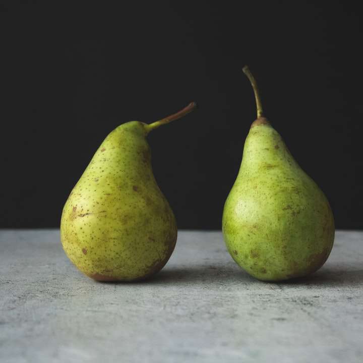 Dos frutos de pera verde sobre textil blanco rompecabezas en línea