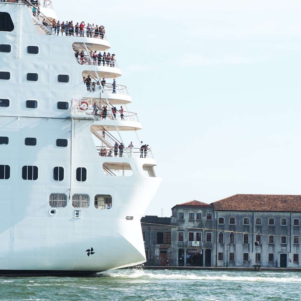 бял кораб на водно тяло близо до кафява бетонна сграда онлайн пъзел