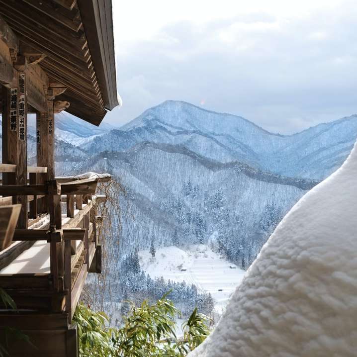 καφέ ξύλινο σπίτι κοντά στο χιονισμένο βουνό κατά τη διάρκεια της ημέρας συρόμενο παζλ online