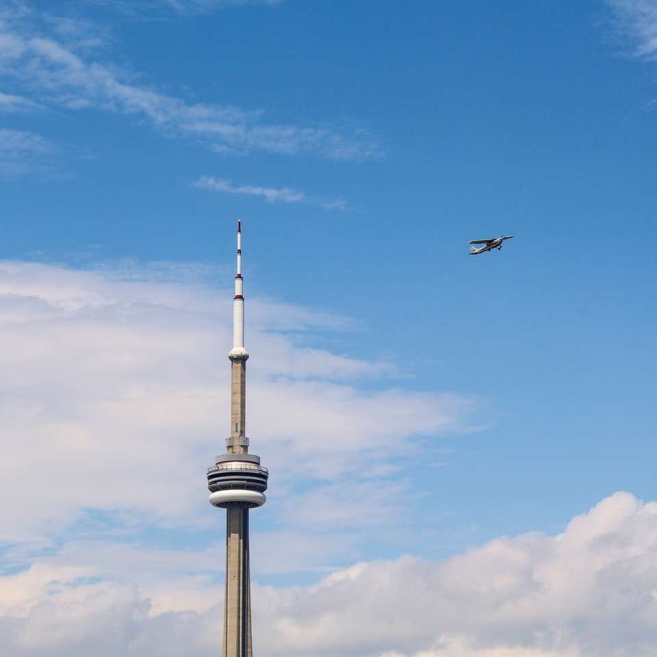 uccello nero che vola sopra la torre bianca sotto il cielo blu puzzle scorrevole online