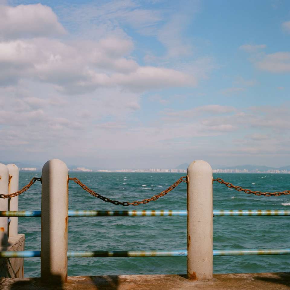 Muelle de madera marrón sobre el mar azul bajo nubes blancas rompecabezas en línea