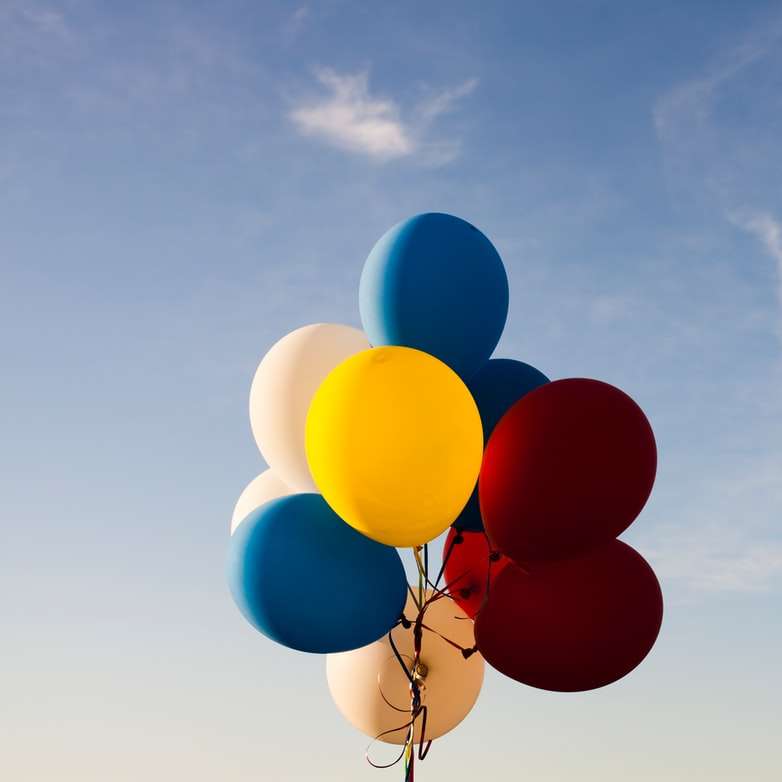 palloncini bianchi, gialli, rossi e blu sotto il cielo blu puzzle scorrevole online