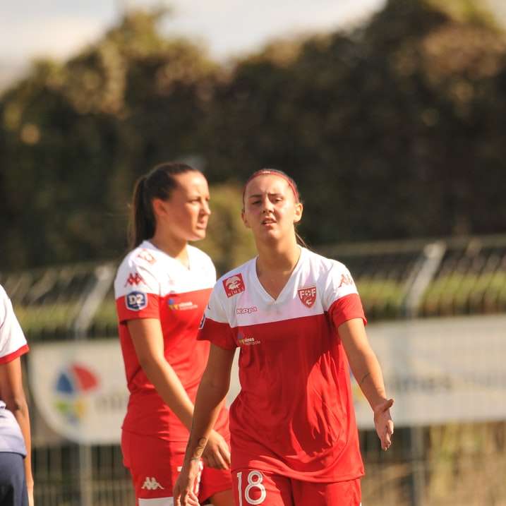 2 γυναίκες με κόκκινη και λευκή στολή ποδοσφαίρου που τρέχουν στο γήπεδο συρόμενο παζλ online