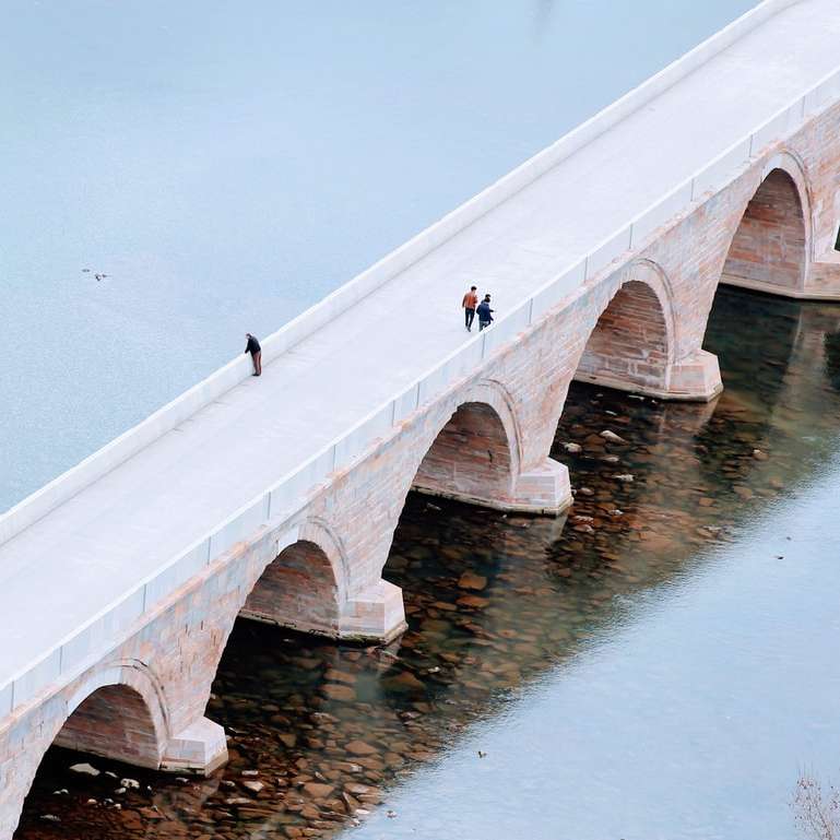 pessoas andando na ponte de concreto branco durante o dia puzzle deslizante online