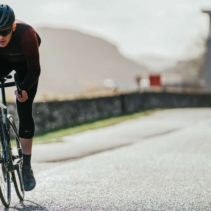 άντρας με κόκκινο φανελάκι ιππασία σε μαύρο ποδήλατο στο δρόμο online παζλ