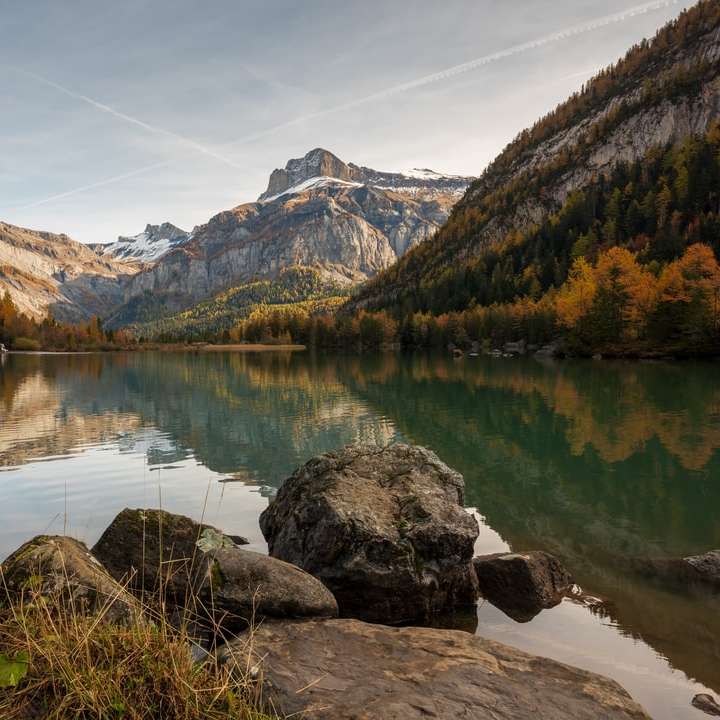 lago cerca de la montaña bajo un cielo azul durante el día puzzle deslizante online