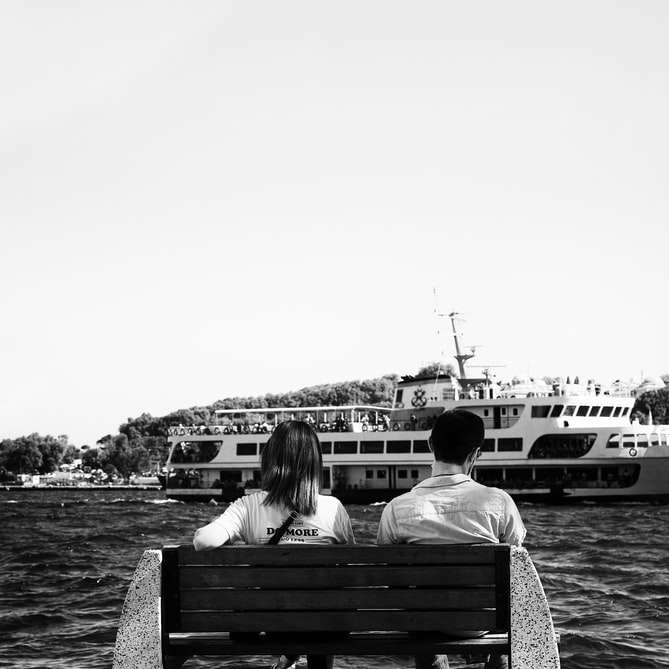 grayscale photo of people sitting on bench near body online puzzle