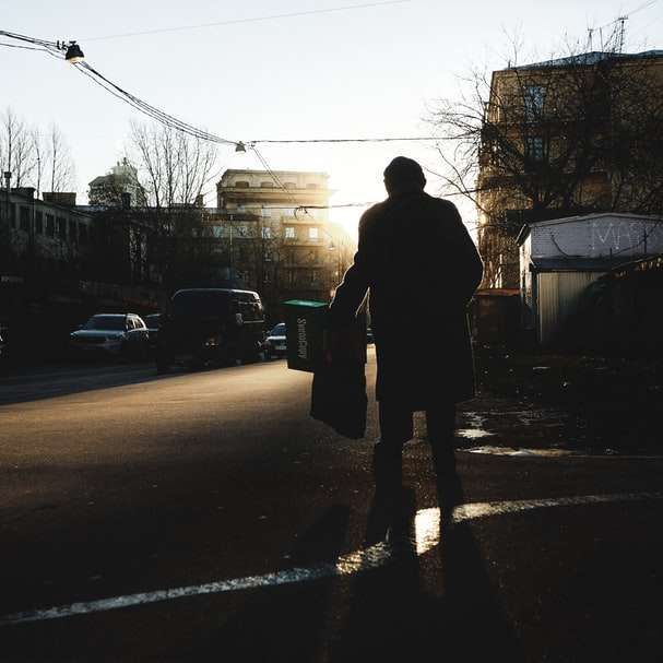 muž v černé bundě stojící na silnici během dne posuvné puzzle online