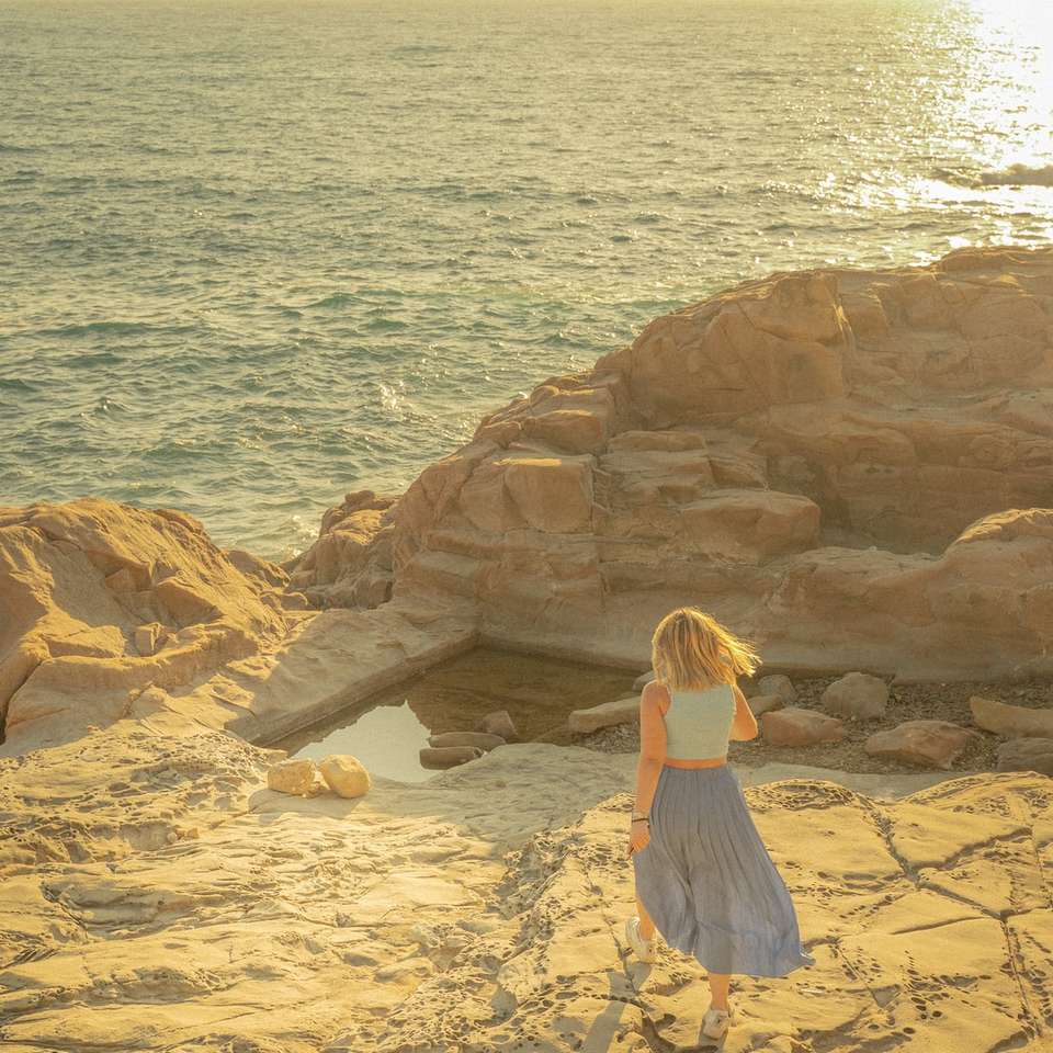 体の近くの茶色の岩の上に座っている白いドレスの女性 スライディングパズル・オンライン