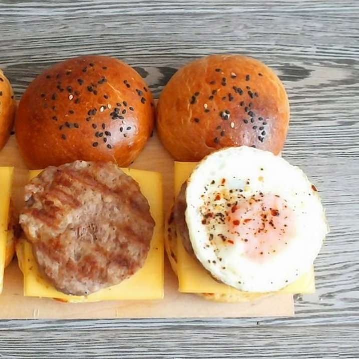 Dos hamburguesas con queso y huevo en placa de cerámica blanca puzzle deslizante online