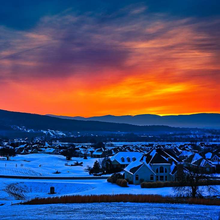 σπίτια σε χιονισμένο έδαφος κατά το ηλιοβασίλεμα συρόμενο παζλ online