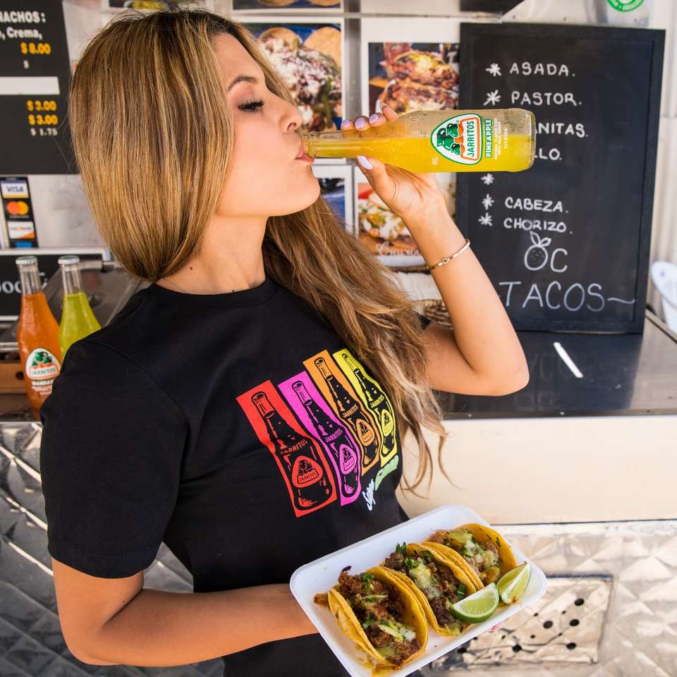 женщина в черной футболке с круглым вырезом ест гамбургер онлайн-пазл