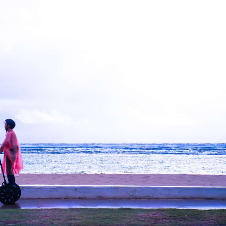 άντρας με κόκκινο πουκάμισο και μαύρο παντελόνι στέκεται στην παραλία συρόμενο παζλ online