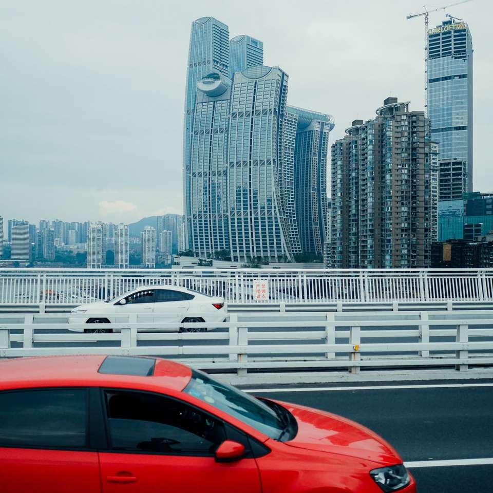 red car on road near city buildings during daytime sliding puzzle online