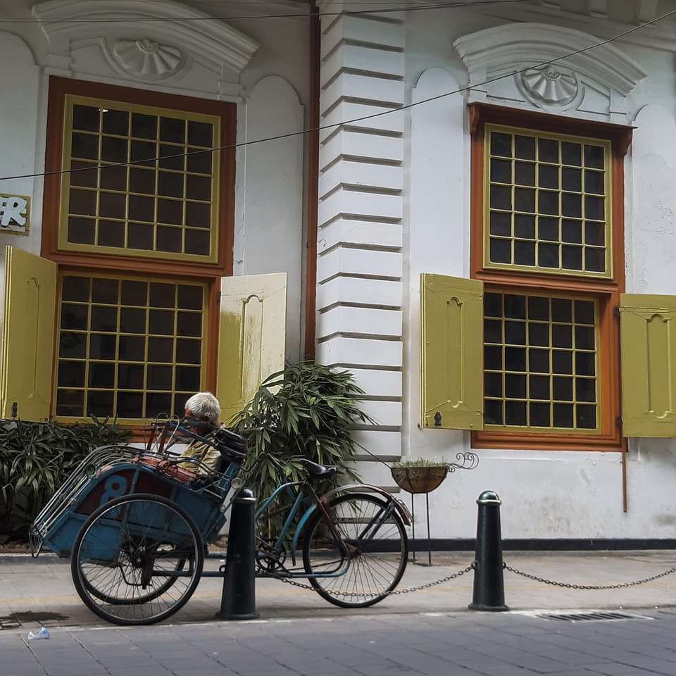 Vélo de ville bleu garé à côté du bâtiment en béton blanc et brun puzzle coulissant en ligne