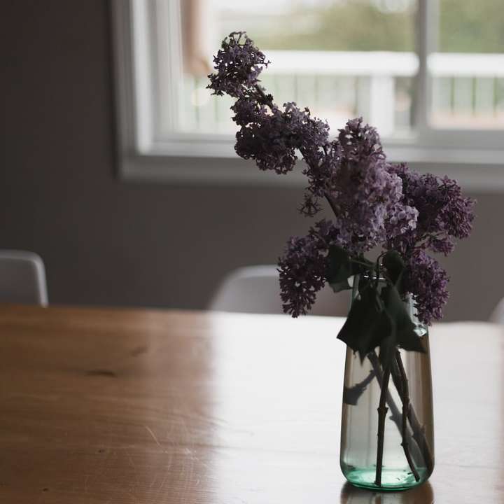 lila blommor i grön glasvas på bordet Pussel online