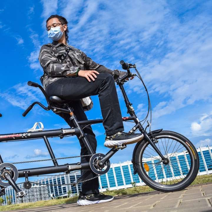 γυναίκα με μαύρο σακάκι ιππασία σε μαύρο ποδήλατο κατά τη διάρκεια της ημέρας συρόμενο παζλ online