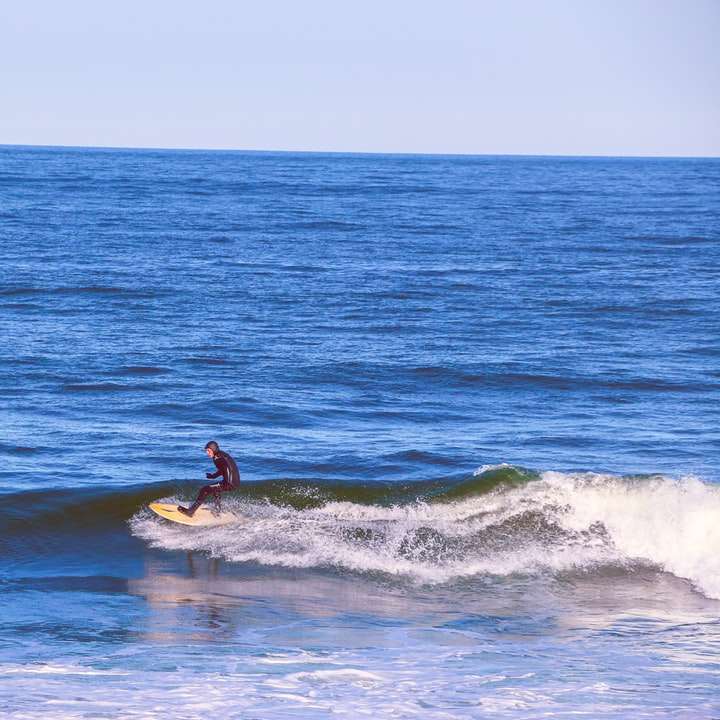людина серфінг на морських хвилях вдень онлайн пазл