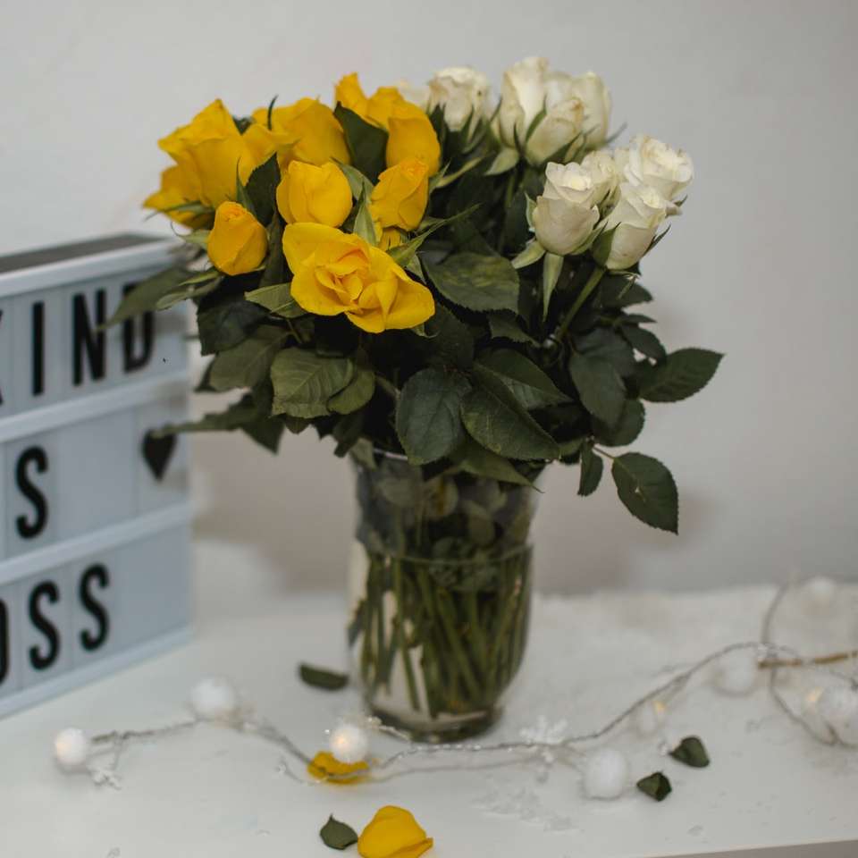 gelbe Blumen in klarer Glasvase auf weißem Schnee Schiebepuzzle online