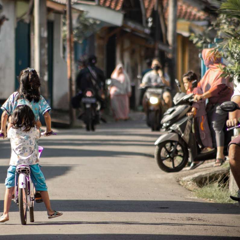flicka i blå och vit klänning ridcykel på vägen Pussel online