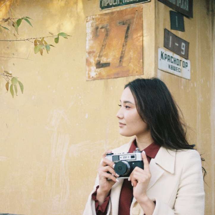 donna in camice bianco che tiene macchina fotografica grigia puzzle online