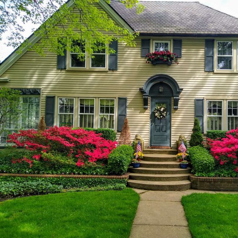 γκρι τσιμεντένιο σπίτι με κόκκινα λουλούδια στο πλάι online παζλ
