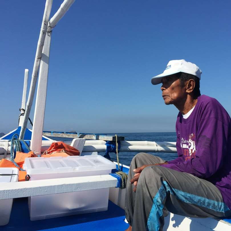 мъж с лилав качулка и сиви панталони, седнал на лодка плъзгащ се пъзел онлайн