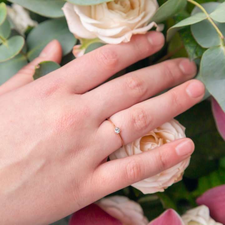 person wearing gold wedding band holding white rose online puzzle