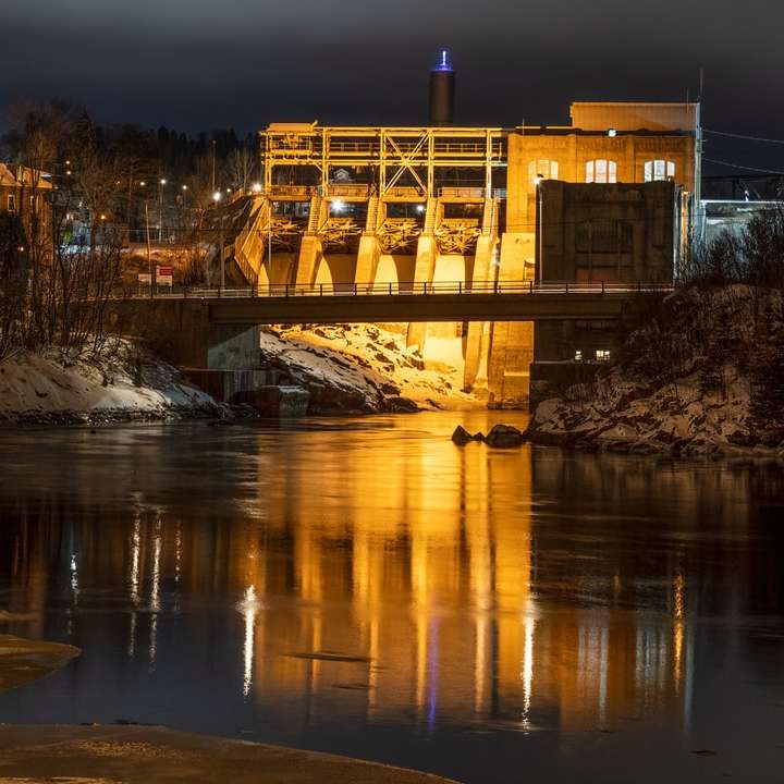 edifício de concreto marrom perto da ponte durante a noite puzzle deslizante online