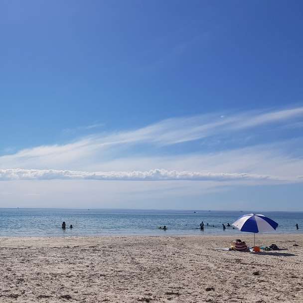 människor på stranden under dagtid glidande pussel online