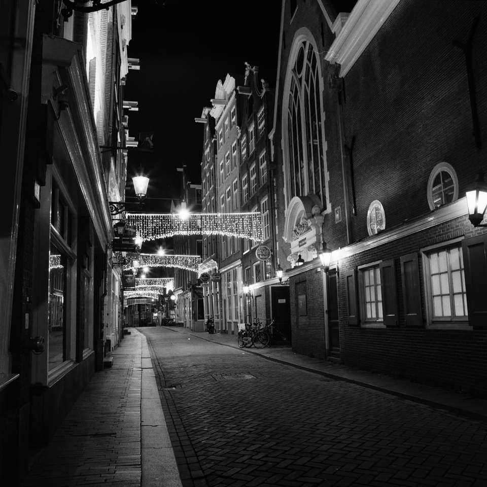 grayscale photo of a street in between buildings online puzzle