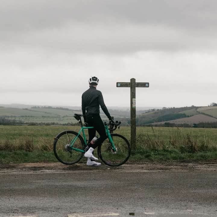 uomo in giacca nera cavalcando mountain bike verde su strada puzzle scorrevole online