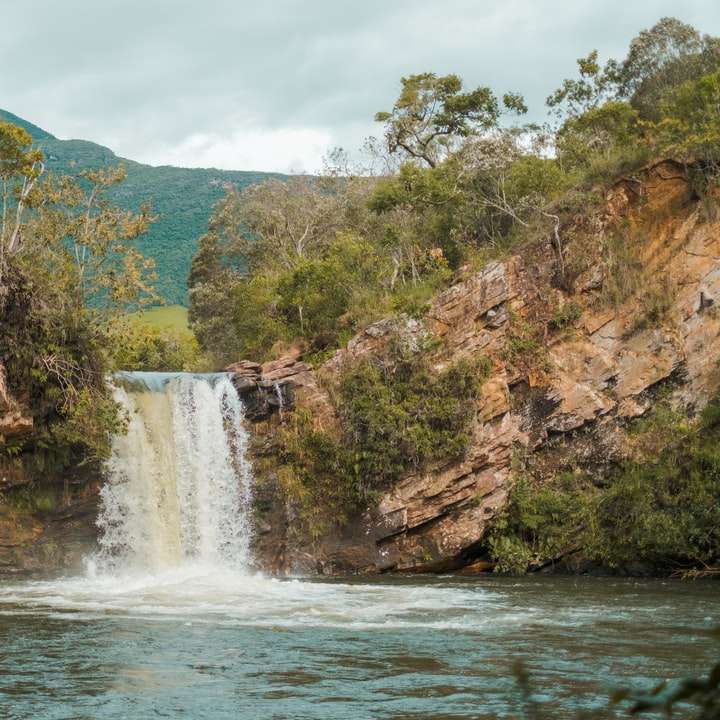 водопади близо до зелени дървета под бяло небе през деня плъзгащ се пъзел онлайн