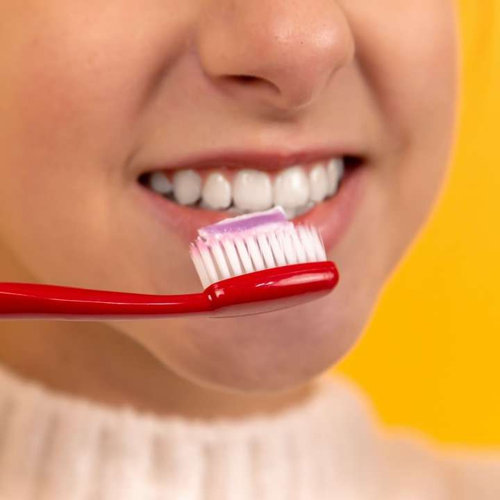 口の中に赤と白の歯ブラシを持つ女の子 スライディングパズル・オンライン