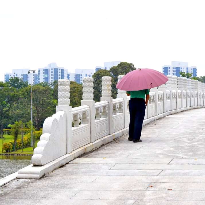 Frau in der schwarzen Hose, die rosa Regenschirm hält Online-Puzzle
