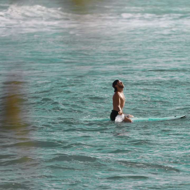 mulher de biquíni preto surfando no mar durante o dia puzzle online