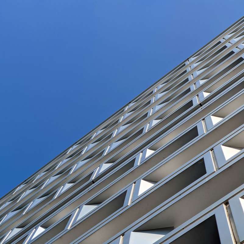 бяла бетонна сграда под синьо небе през деня онлайн пъзел